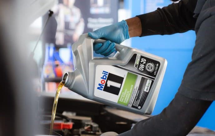 Technician pouring Mobil 1 motor oil during a service